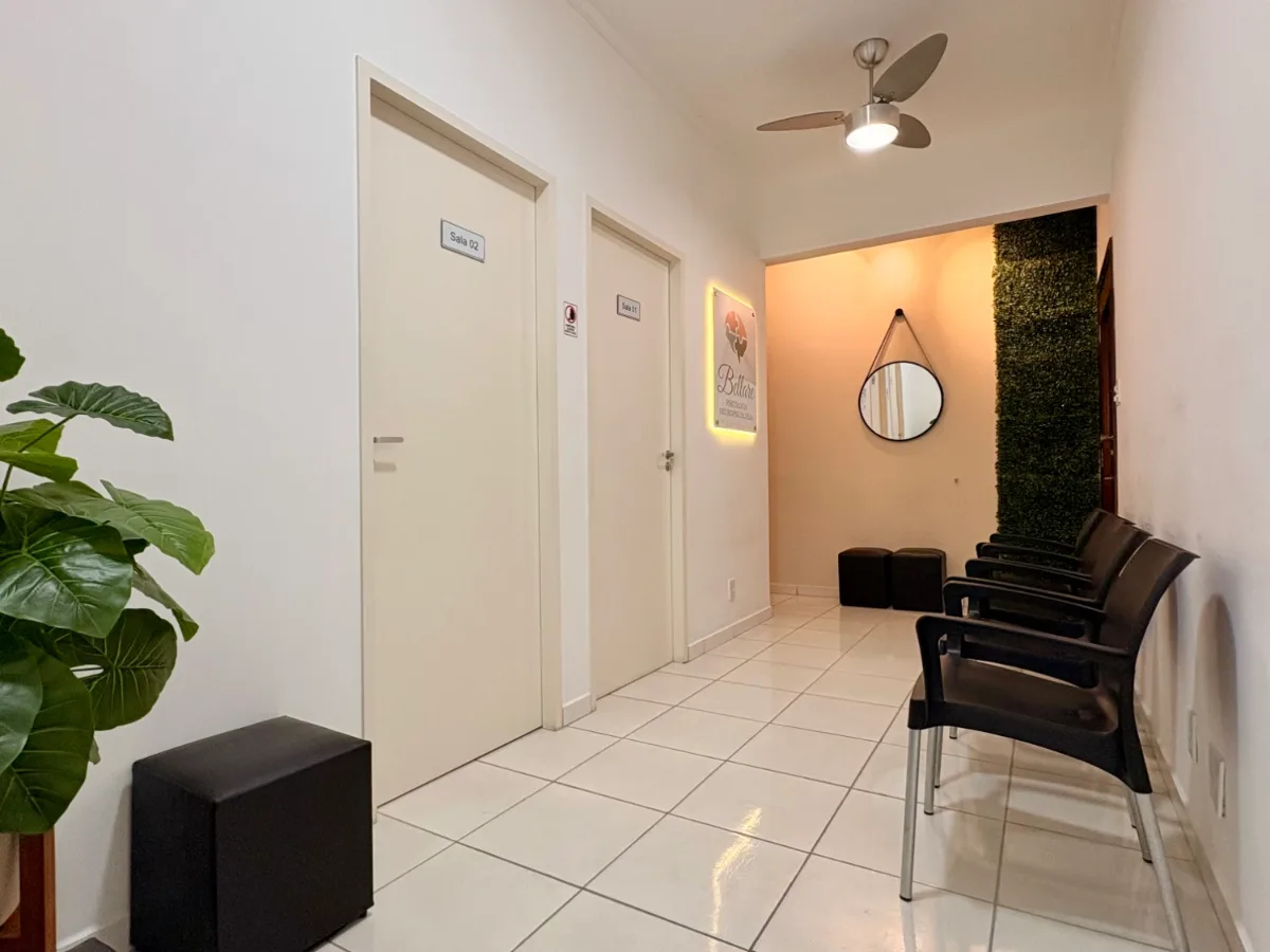 Sala de espera da Clínica Bellare, com cadeiras, portas das salas de atendimento e parede verde ao fundo